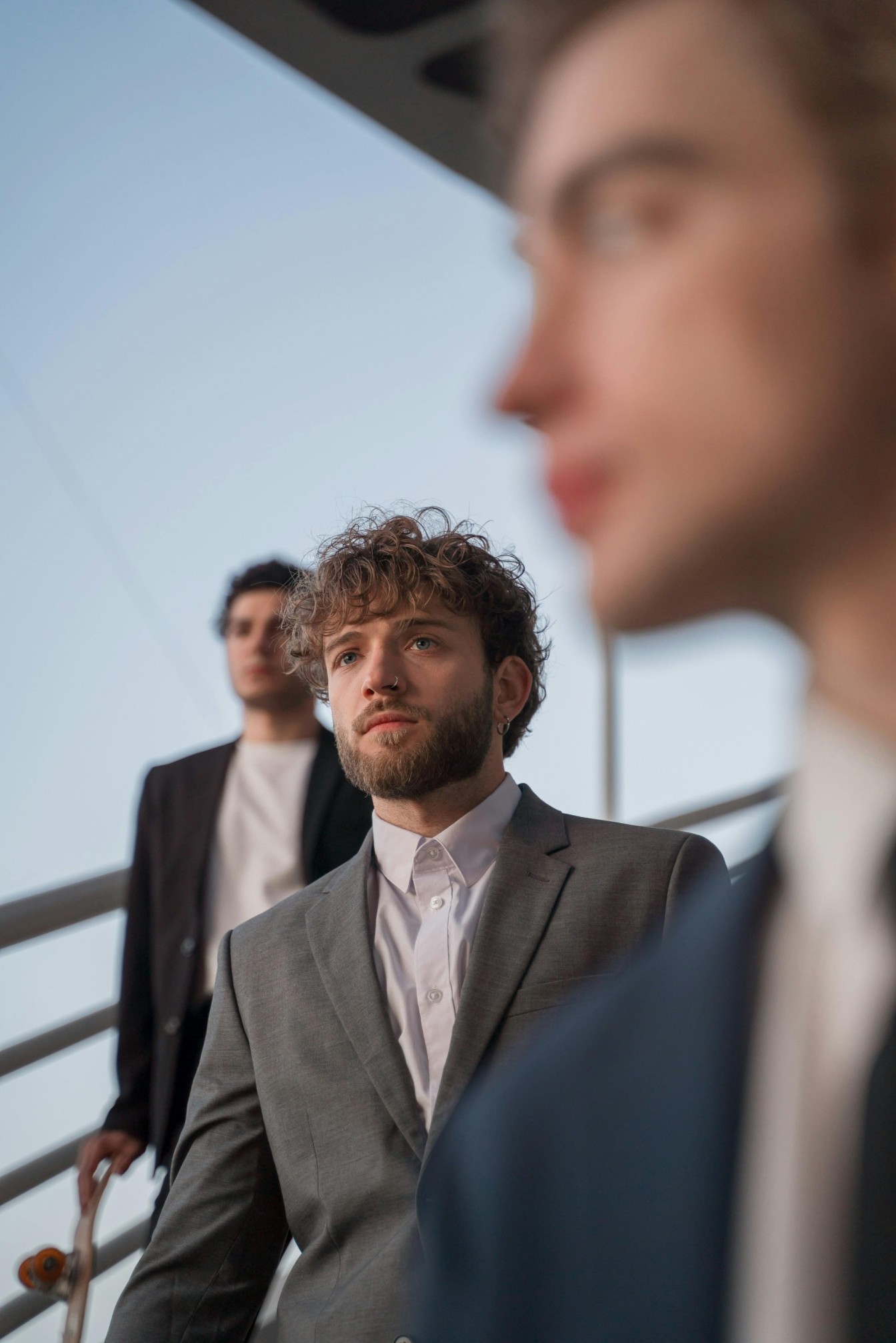 Three young professionals in suits walking with urban architecture backdrop.